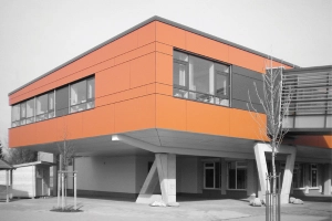 Durch den hohen Vorfertigungsgrad konnte die Aufstockung der Schule in Bruchköbel in enorm kurzer Bauzeit realisiert werden. Die orangefarbenen Fassadentafeln machen eine unverwechselbare Landmarke aus dem Gebäude.  Foto: hkr.architekten, Gelnhausen
