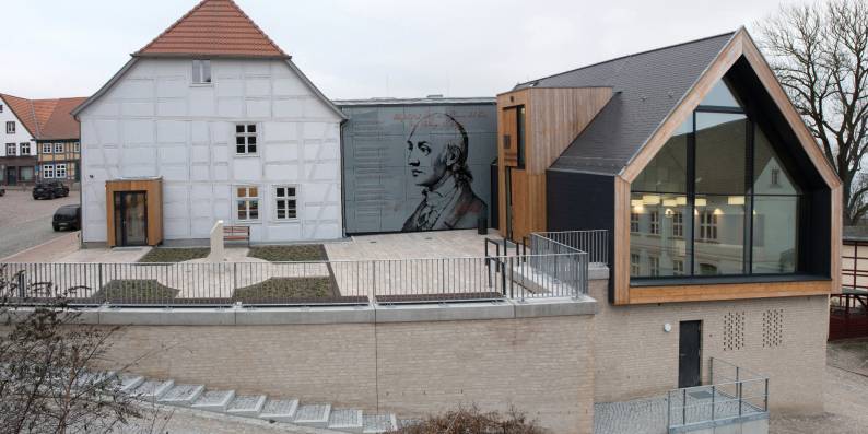 Der moderne Neubau komplettiert das Ensemble auf sinnfällige Weise. Der brückenartige Verbindungsbau führt vom Untergeschoss der ehemaligen Stadtschule ins Obergeschoss des Neubaus und beherbergt das Treppenhaus, sowie einen Aufzug für die barrierefreie Erreichbarkeit aller Geschosse.
