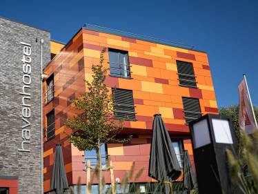 Havenhostel Stade – Moderne Plattenfassade in drei Rottönen