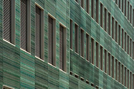 Für die Keramikfassade entwickelten die Architekten das Bild eines Laubmantels und definierten drei Grüntöne – die semitransparent lasiert wurden und den keramischen Grundscherben teilweise erkennbar lassen – sowie eine individuelle Oberflächenstruktur mit einer feinen Profilierung aus horizontalen Rillen. Foto: Anke Müllerklein