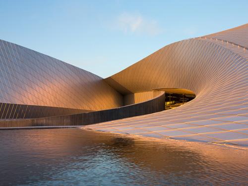 Realisiert mit einer vorgehängten hinterlüfteten Fassade wecken die changierenden Oberflächen und freien Formen Assoziationen an das Element Wasser. Foto: Novelis 