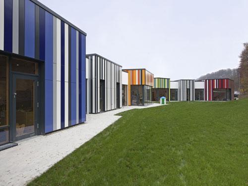Der Blick von Südwesten über die Spielwiese auf die wabenförmigen Gruppenhäuser zeigt, dass jede Wabe über die vorgehängte hinterlüftete Fassade einen anderen Farbeindruck vermittelt. Die Kinder erhalten so Orientierungshilfen. Foto: MOEDING Keramikfassaden GmbH (Toni Ott, Landshut)