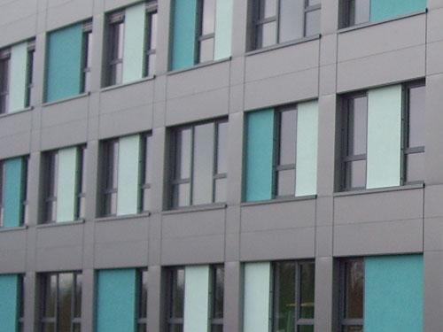 Das geometrische Fassadenraster der grauen VHF wird durch die Mintgrüne und türkise Fenstergestaltung aufgelockert. Foto: AS Fassaden GmbH