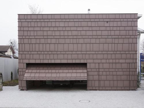 Die Garage mit Spa erhält durch die vorgehängte hinterlüftete Fassade einen monolithischen Charakter. Auch das Garagentor ist mit einer Zink-Bekleidung bedeckt. Foto: Paul Kozlowski